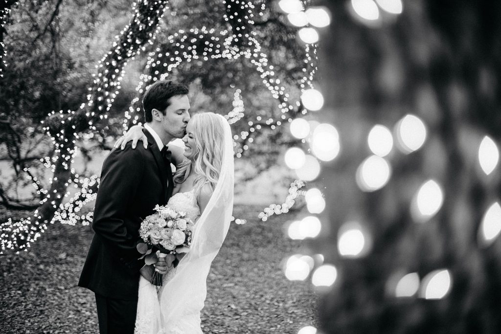 Black and white portrait of Bride and Groom by a lit tree after their wedding ceremony at the Houstonian