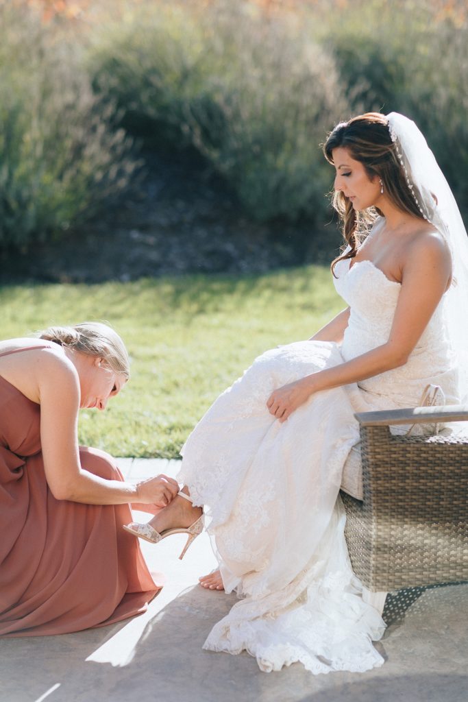Bridesmaid assisting Bride with putting on her shoe at Napa Valley wedding