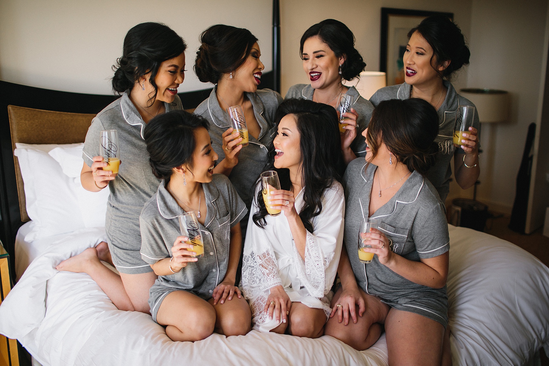Bride and Bridesmaids on their bed at their hotel preparing for the wedding