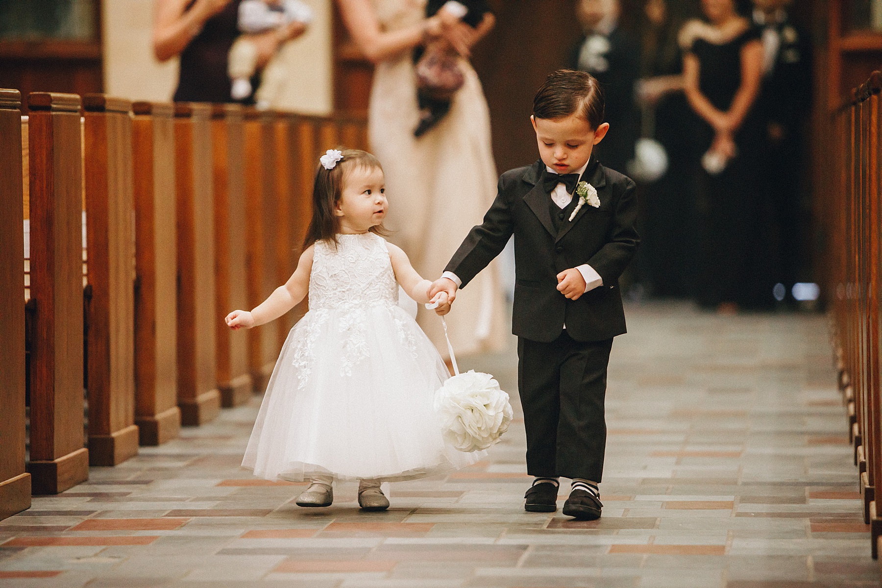 Sweet flower girl and page boy walk down the aisle together 